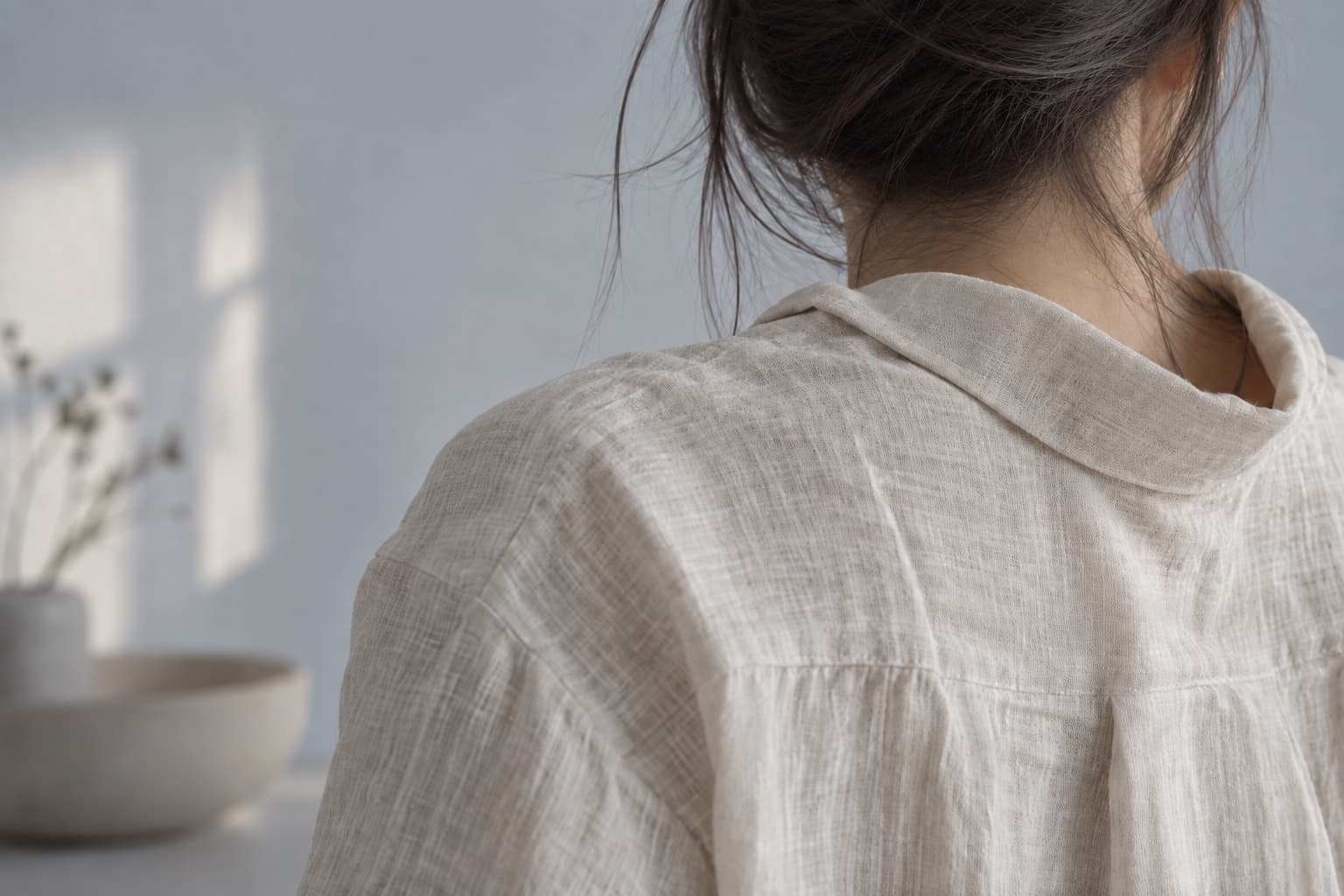 白いリネンをまとった女性の肩と後ろ姿